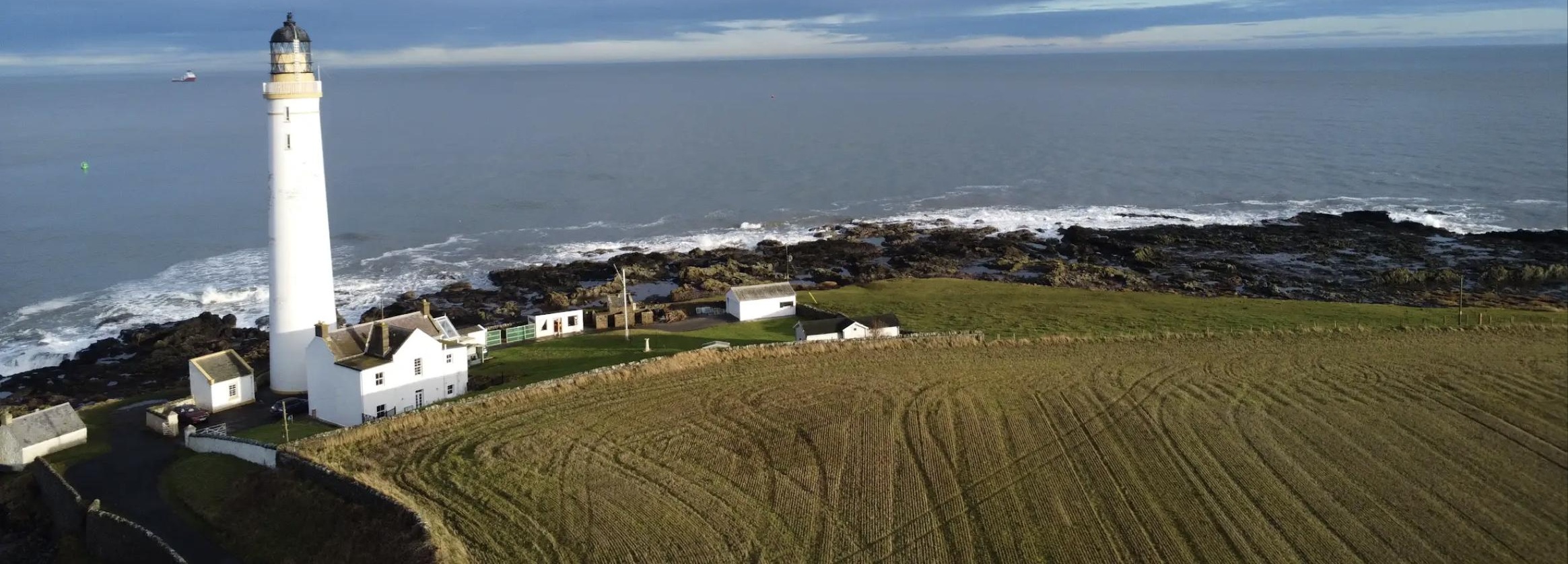 Maritime Compliance Services — Coastal Lighthouse Aerial view of a coastal lighthouse and rocky shoreline, illustrating NautikOne's maritime compliance services